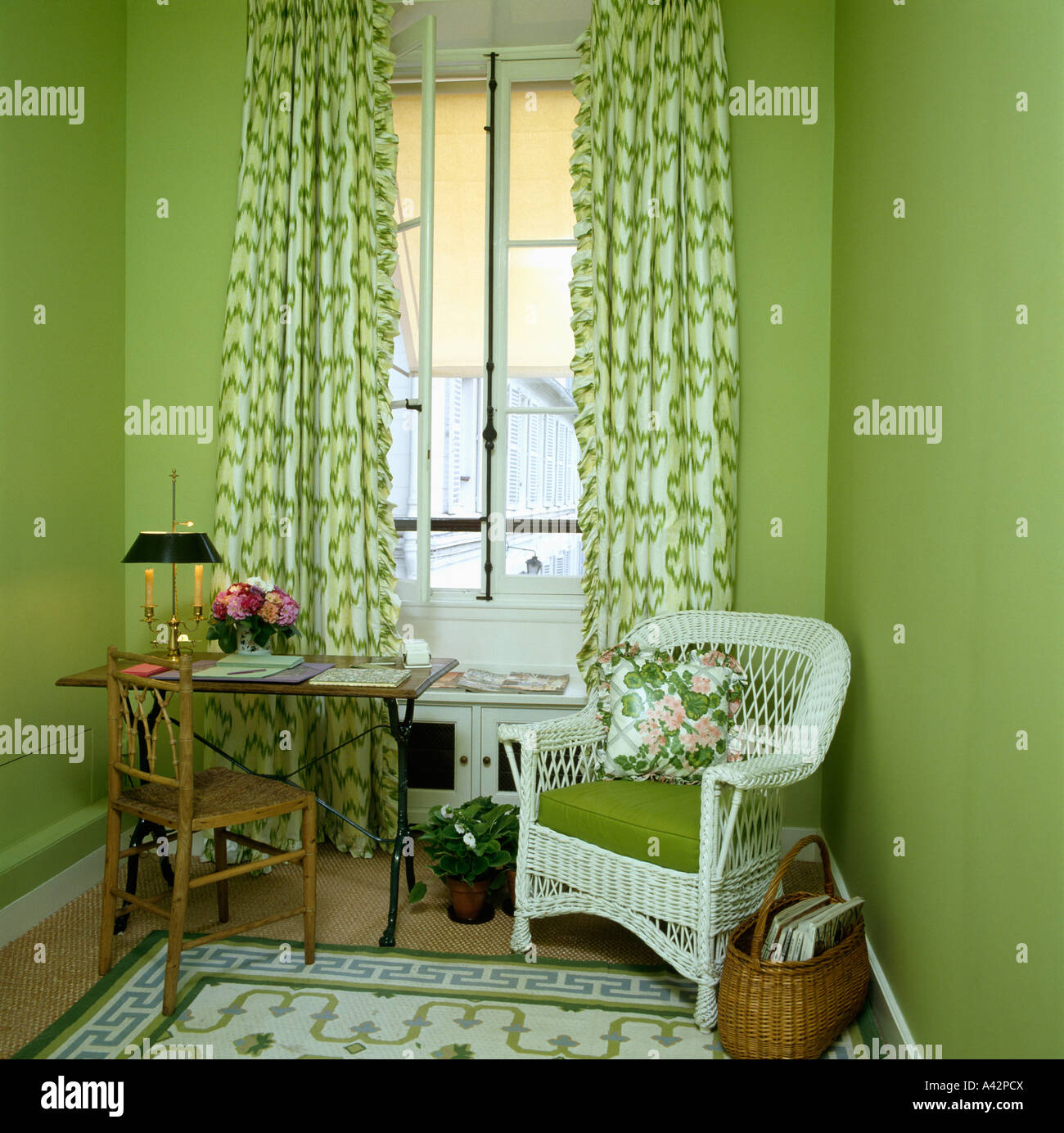 Pequeña sala verde con verde y blanco y cortinas estampadas y silla de  mimbre blanco con cojín verde Fotografía de stock - Alamy