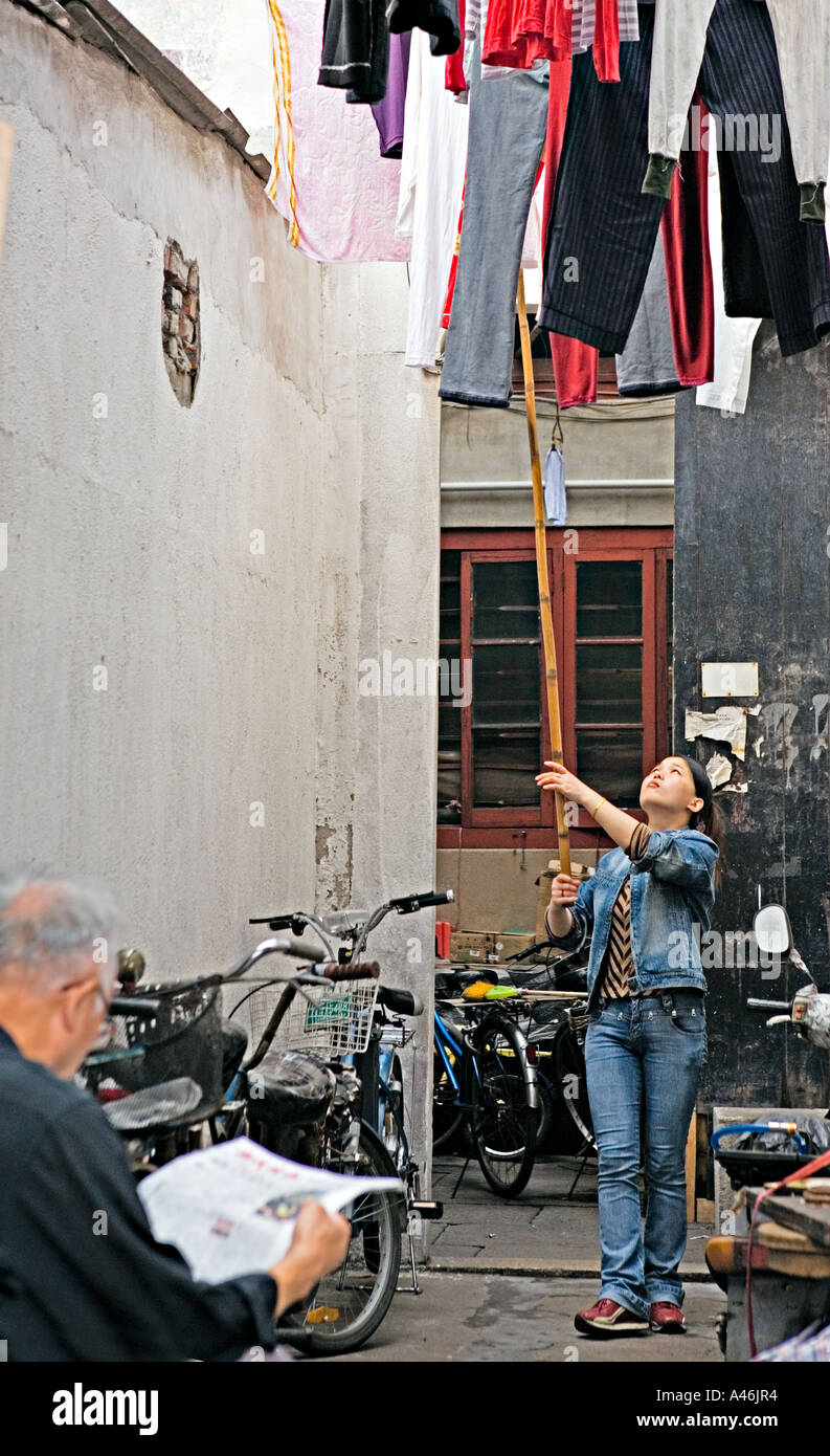 CHINA SHANGHAI joven China quitando el secado la ropa tendedero en el callejón con polo de bambú largo Fotografía de stock - Alamy