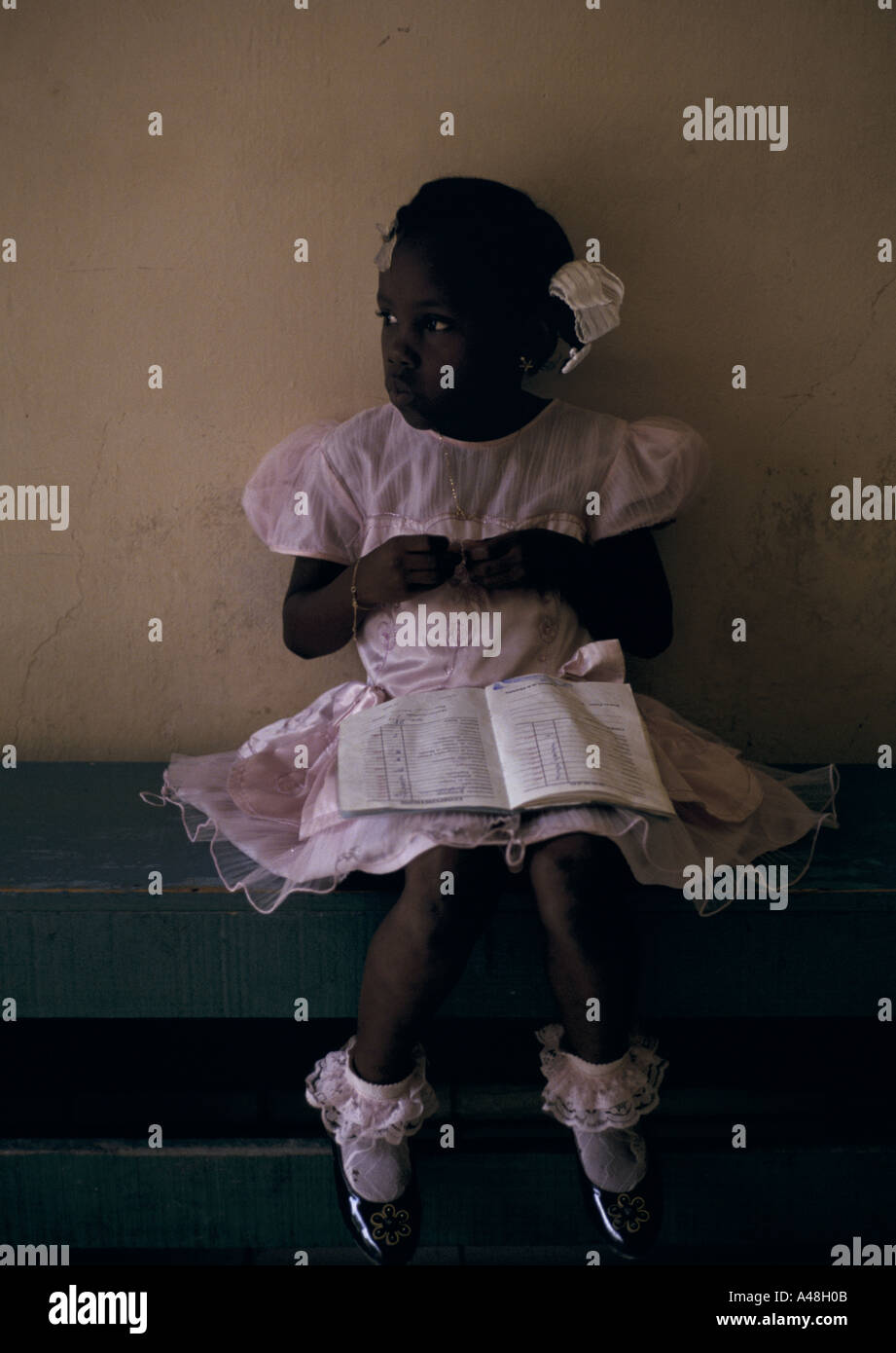 Pequeña niña haitiana con un libro de ejercicios en una escuela en Puerto Príncipe, Haití Foto de stock