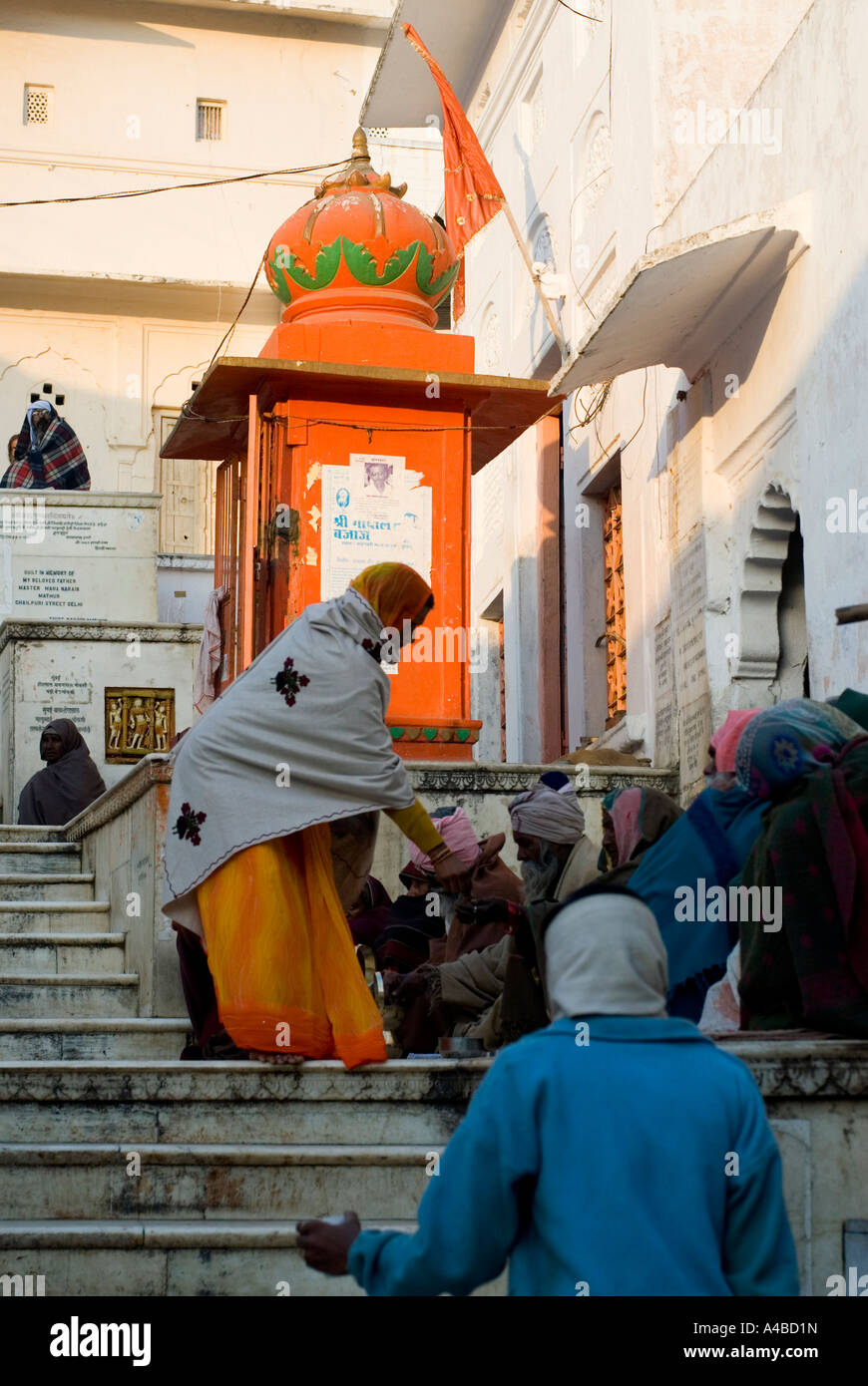 Imágenes de stock de una mujer india, una naranja en Sari, dar limosnas a los mendigos Foto de stock