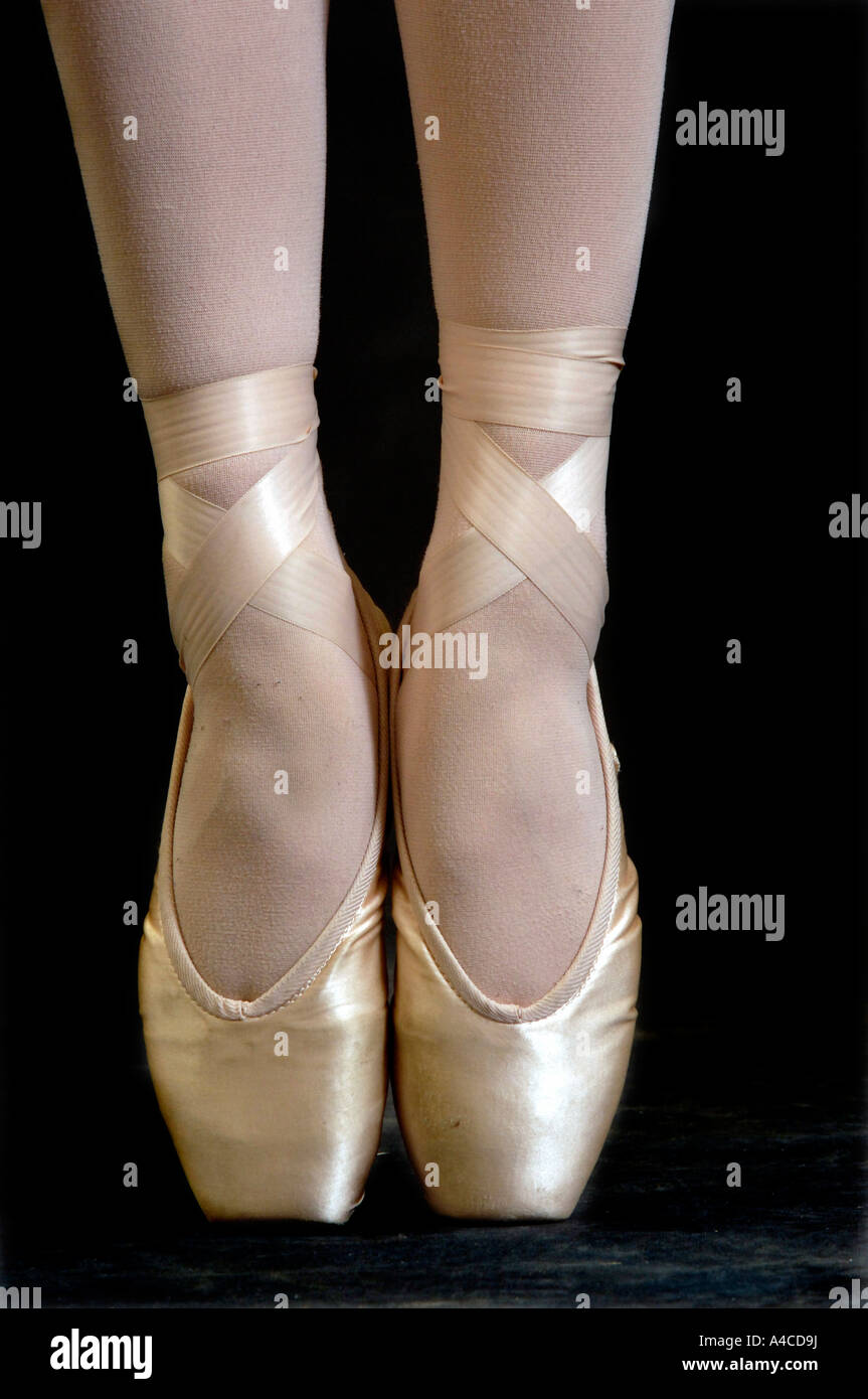 Cerca del pie de una bailarina en puntos en los zapatos de ballet Foto de stock