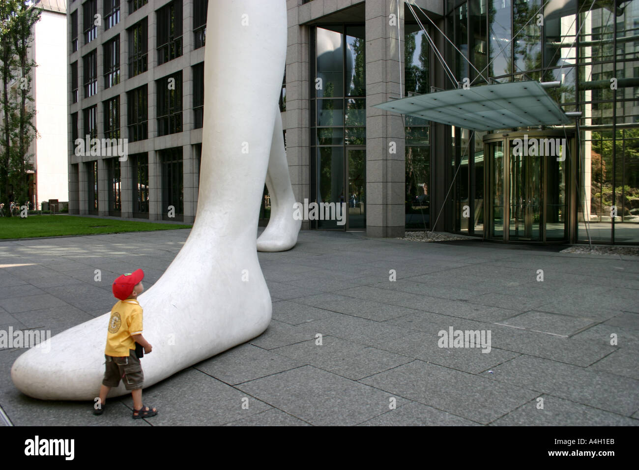 Kid impresionado por big foot caminar hombre delante de Muenchener Rueckversicherung Alemania Baviera Munich Re Foto de stock