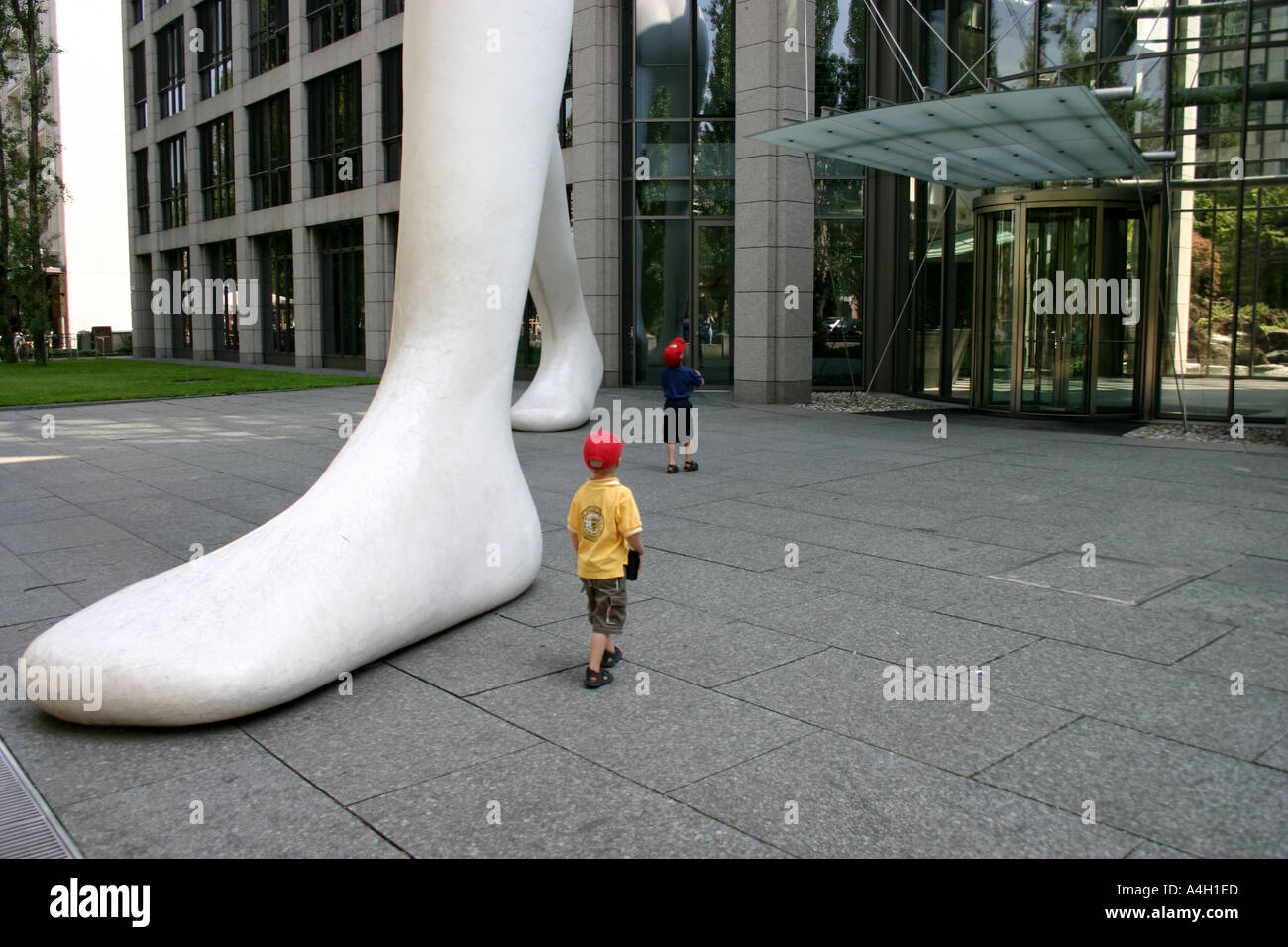 Los niños impresionados por big foot caminar hombre delante de Muenchener Rueckversicherung Alemania Baviera Munich Re Foto de stock