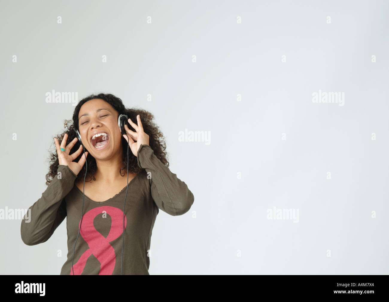 Mujer joven escuchar auriculares, cantando, Retrato Foto de stock