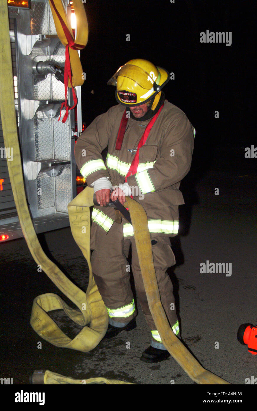 Bombero tirando de una manguera fotografías