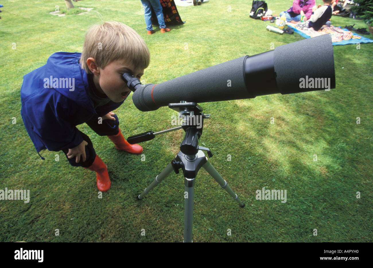 Escuela joven chico mirando a través de un telescopio de observación de aves Foto de stock