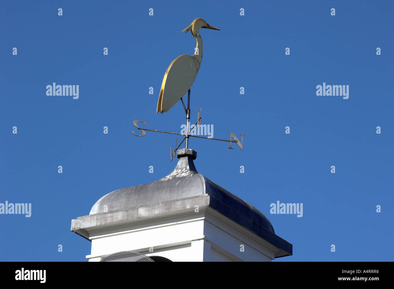 Veleta representando una cigüeña, adornando un tejado contra un cielo azul brillante. Tattenhall cerca de Chester. Foto de stock