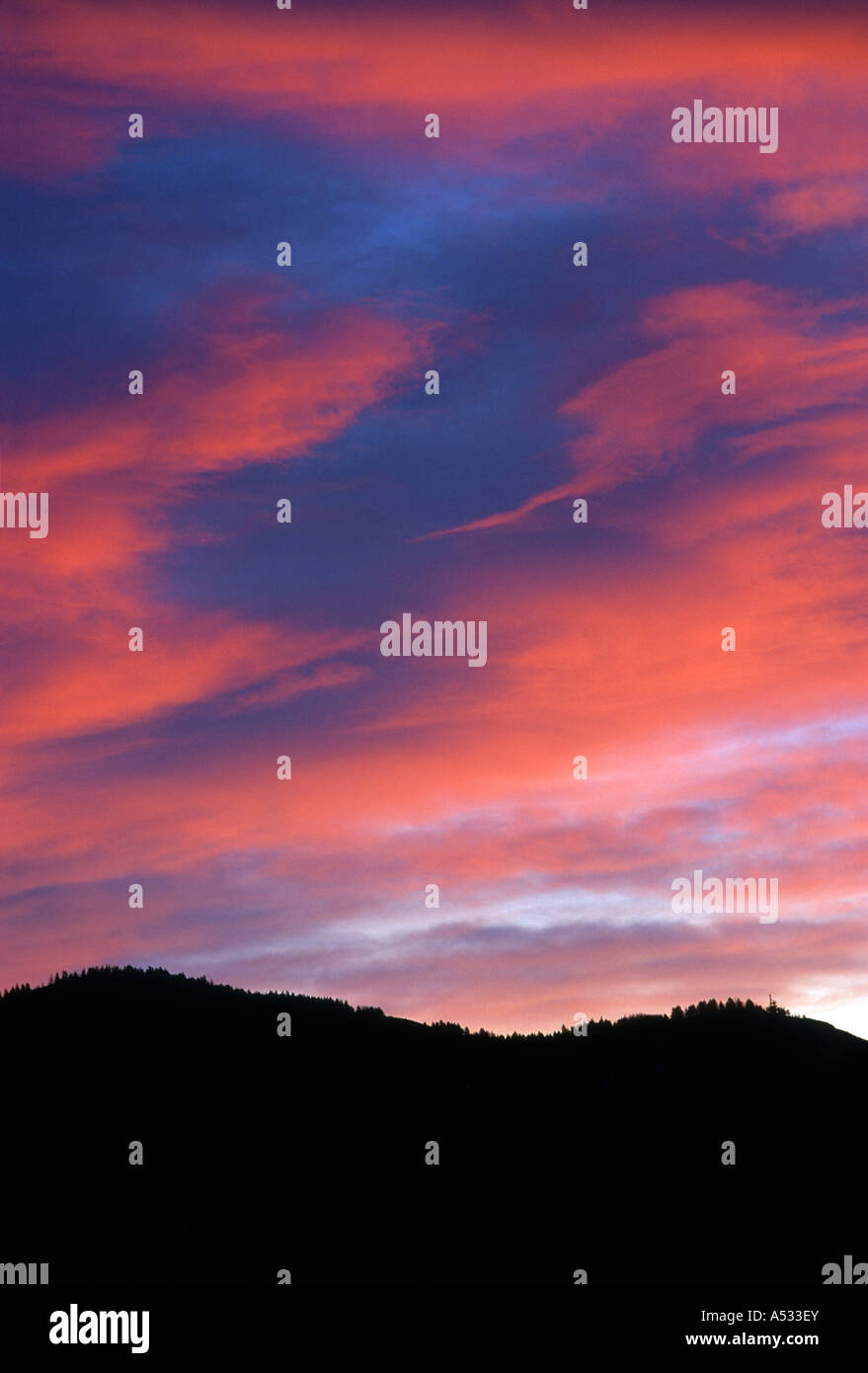 Brillantes Nubes de puesta de sol a lo largo de las crestas de las montañas Foto de stock