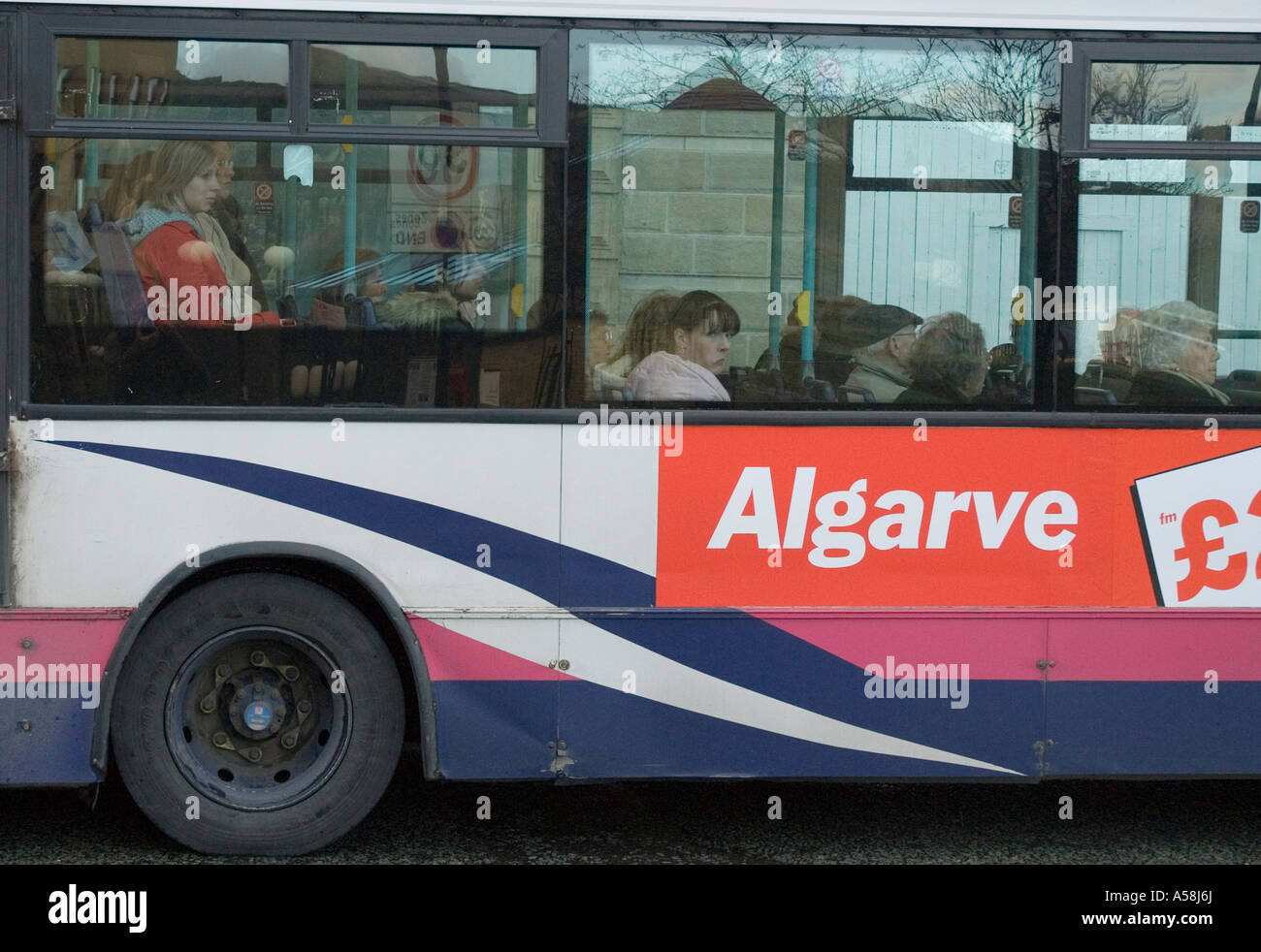 Aburrido buscando pasajeros de un autobús en el exterior tiene un anuncio de vuelos baratos a Algarve Foto de stock