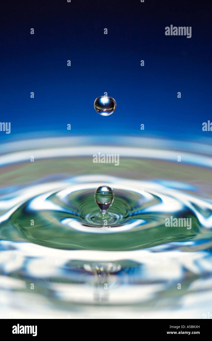 Gotas de agua sobre la superficie de espejo de agua de degradado de color azul. Agua sobre un plato con espejo refleja el color Foto de stock