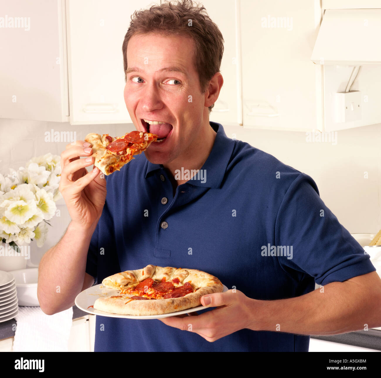 El hombre en la cocina comiendo pizza Fotografía de stock Alamy