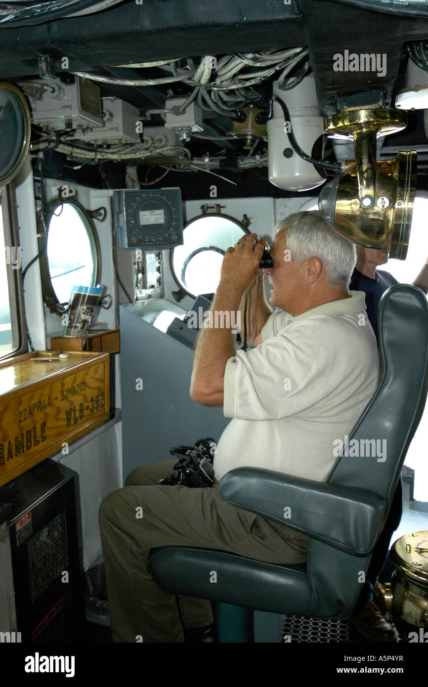 Un capitán de su barco en el puente mirando a través de binoculares. Foto de stock