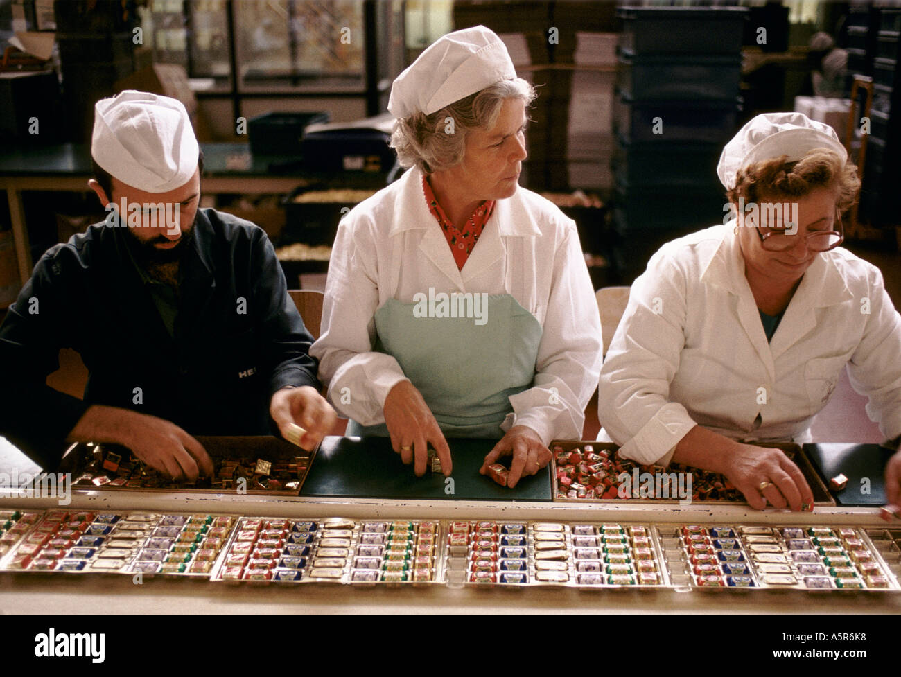 Mujer hombres trabajando de correa transportadora CAFFAREL ENVASES CHOCOLATES LUSERNA SAN GIOVANNI Foto de stock