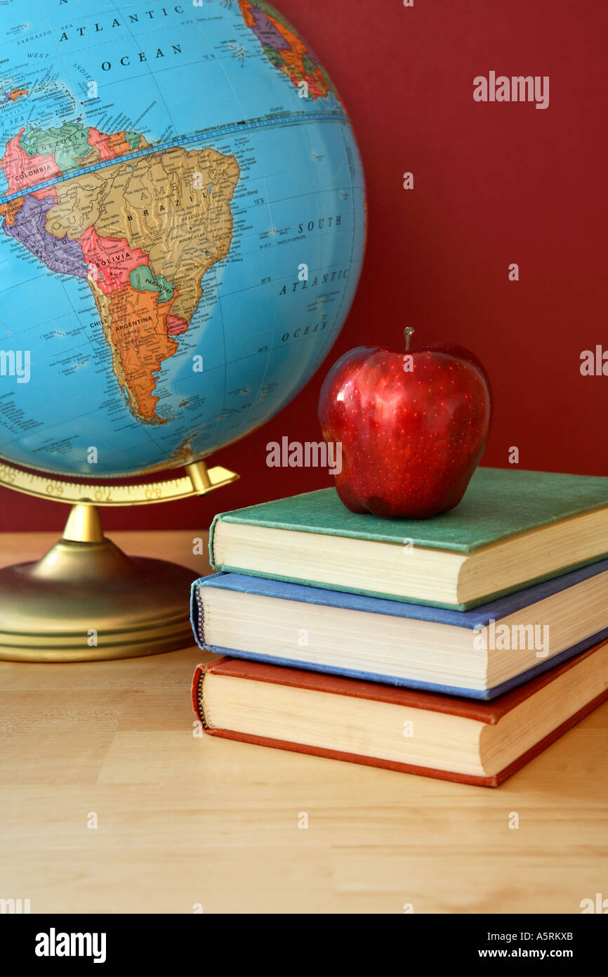 Escuela globe bodegón con libros y manzana roja. Foto de stock