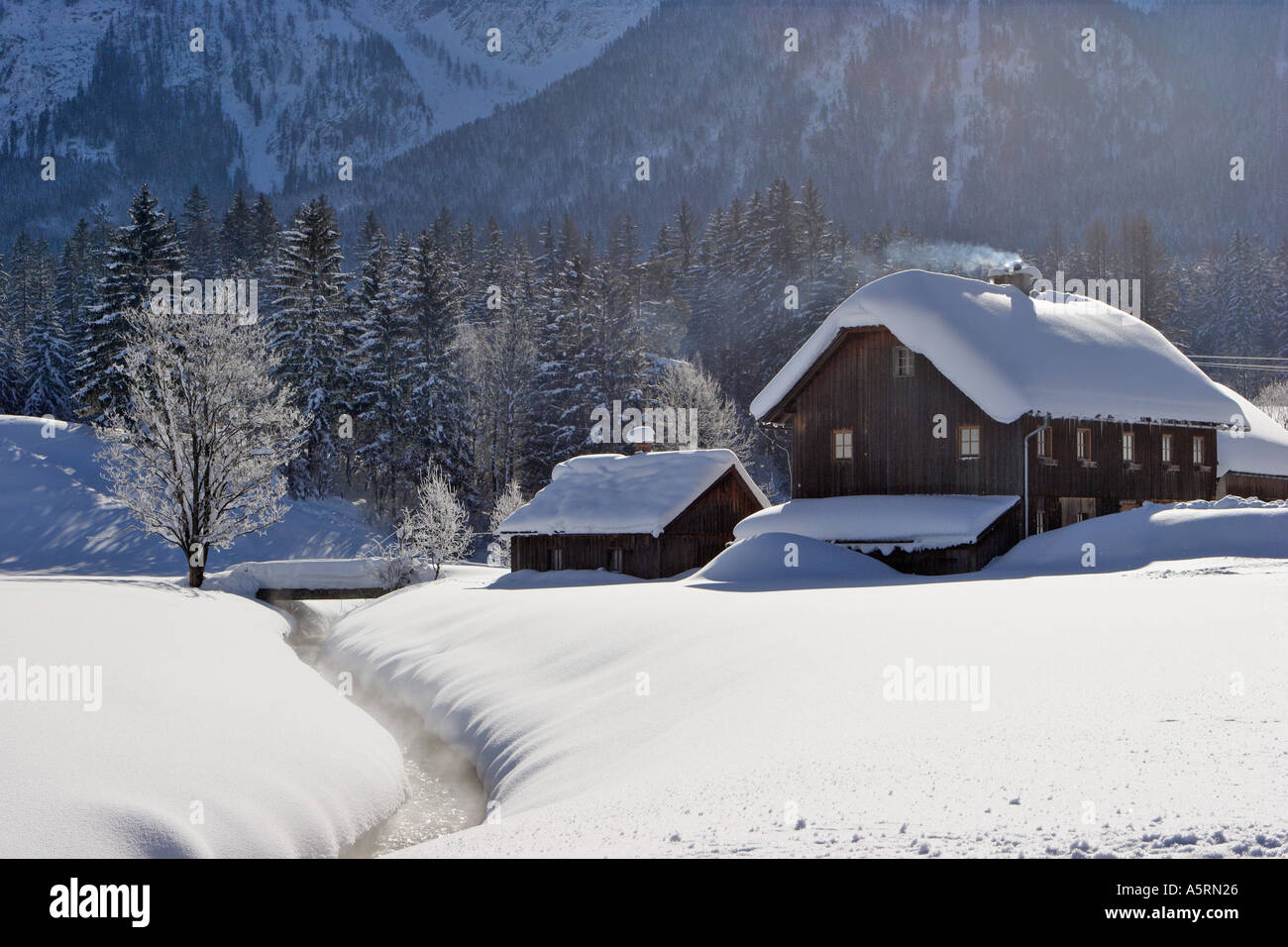Una antigua casa de madera sobre un riachuelo y un montón de nieve krungl estiria austria Foto de stock