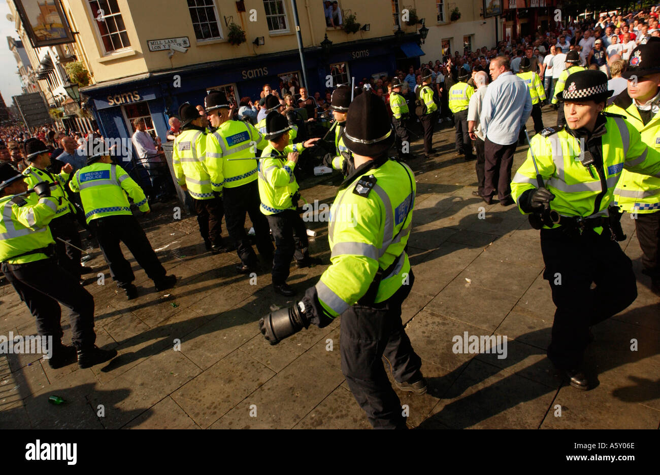 Policías dibujar porras durante problemas entre los hinchas de fútbol de beber alcohol en Mill Lane Cardiff Gales del Sur UK Foto de stock