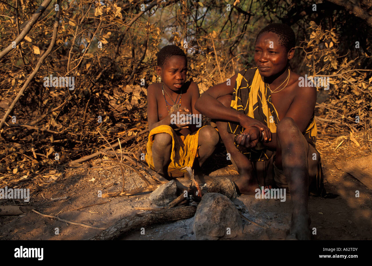 Hadza mujer y niño sentado en un incendio el lago Eyasi de Tanzania pequeña tribu de cazadores-recolectores, conocidos también como los hadzabe Foto de stock