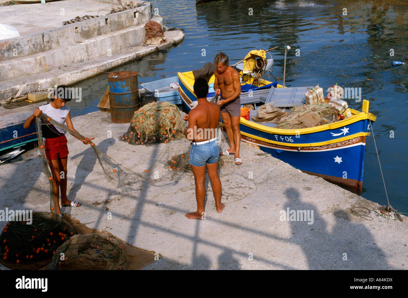 Comprobación de pescadores fishingnet mañana en aldea de Xlendi, isla de Gozo Malta Foto de stock