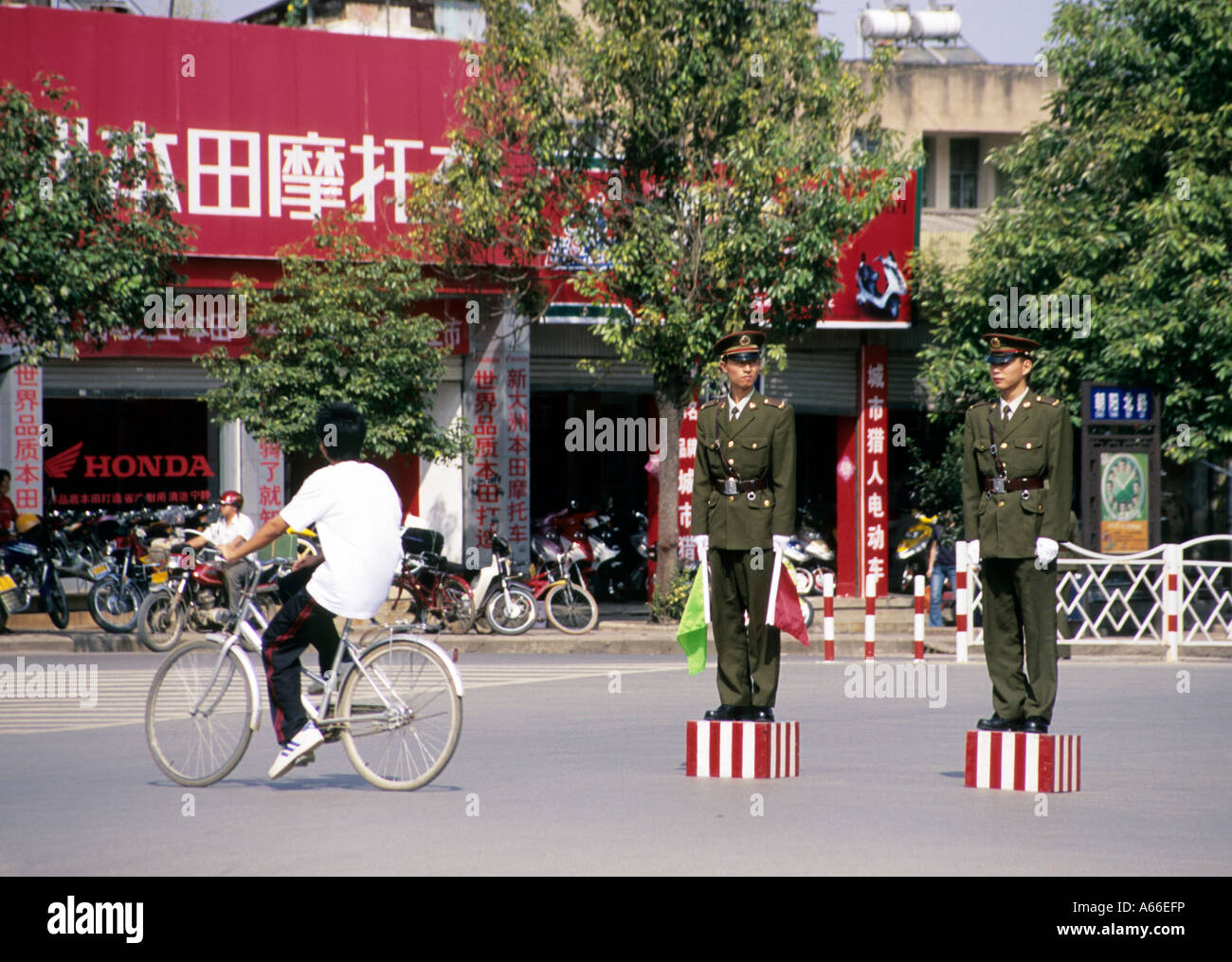 Dos policías de pie en postura tiesa en un cruce, esperando a altos dirigentes políticos que pasan por el lugar. Jianshui, China. Foto de stock