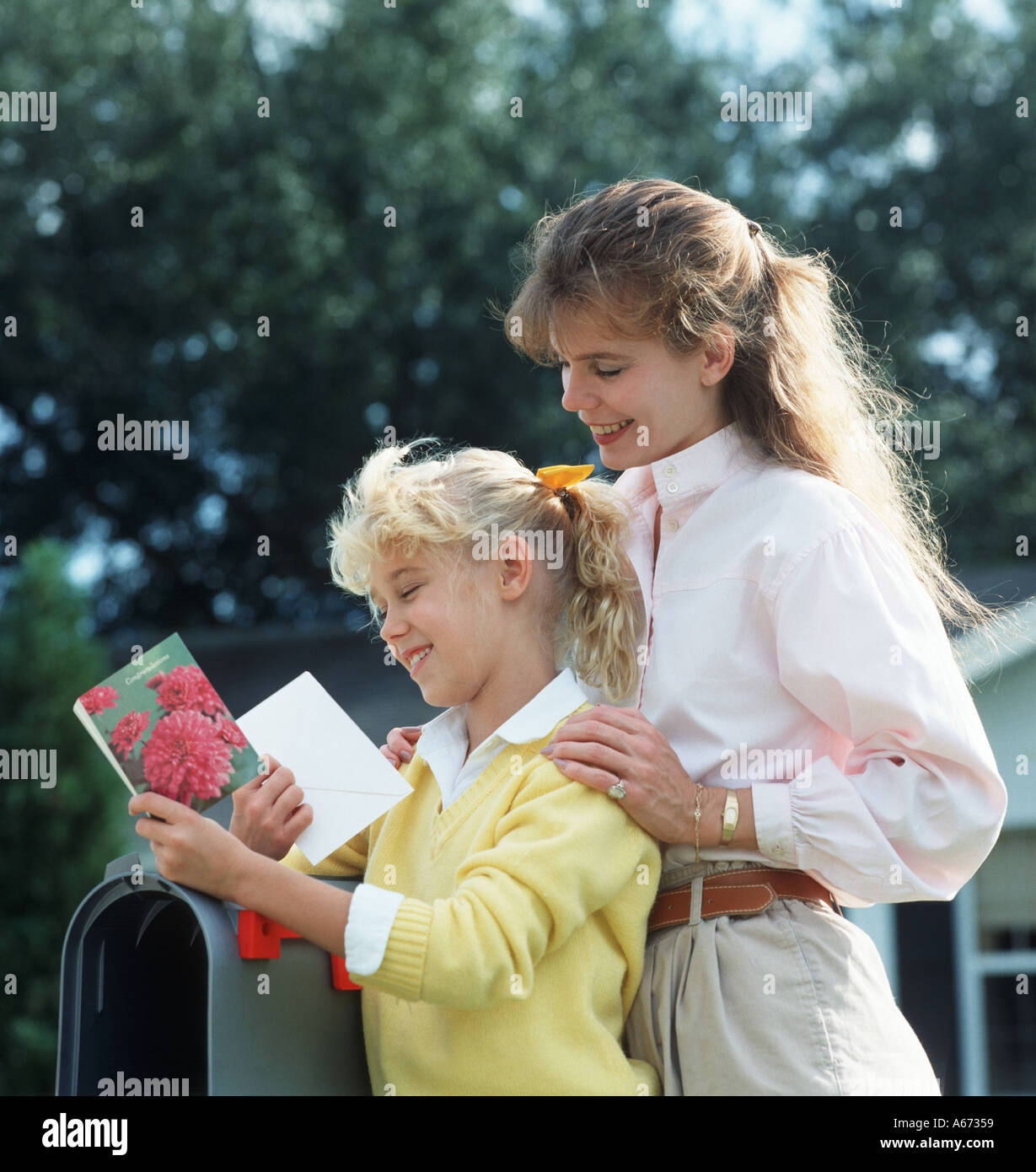 Madre e hija en el buzón una tarjeta de felicitación de lectura Foto de stock