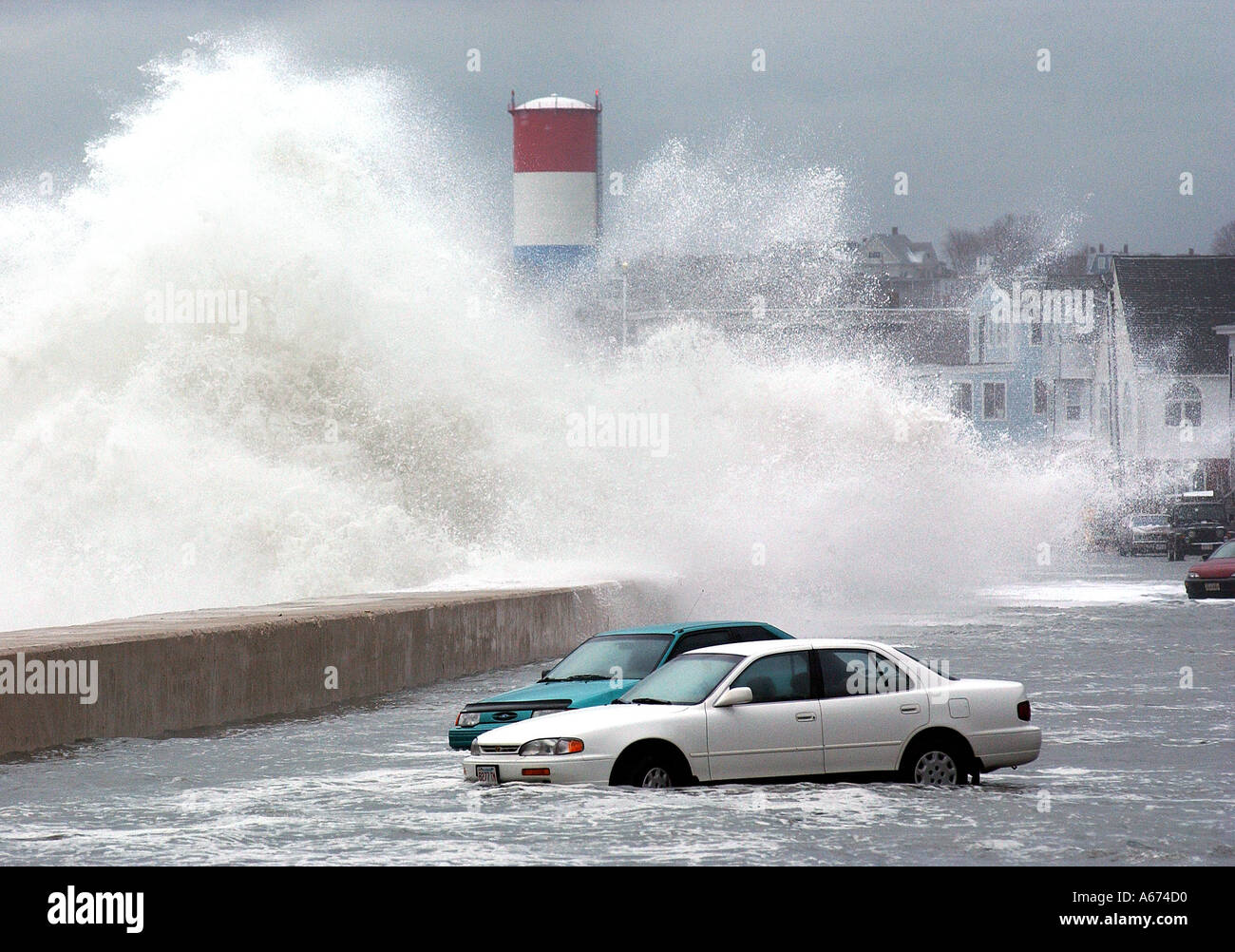 Los vehículos están estancadas en las aguas de la inundación como olas gigantes crash en un rompeolas durante una tormenta de invierno en Massachusetts. Foto de stock