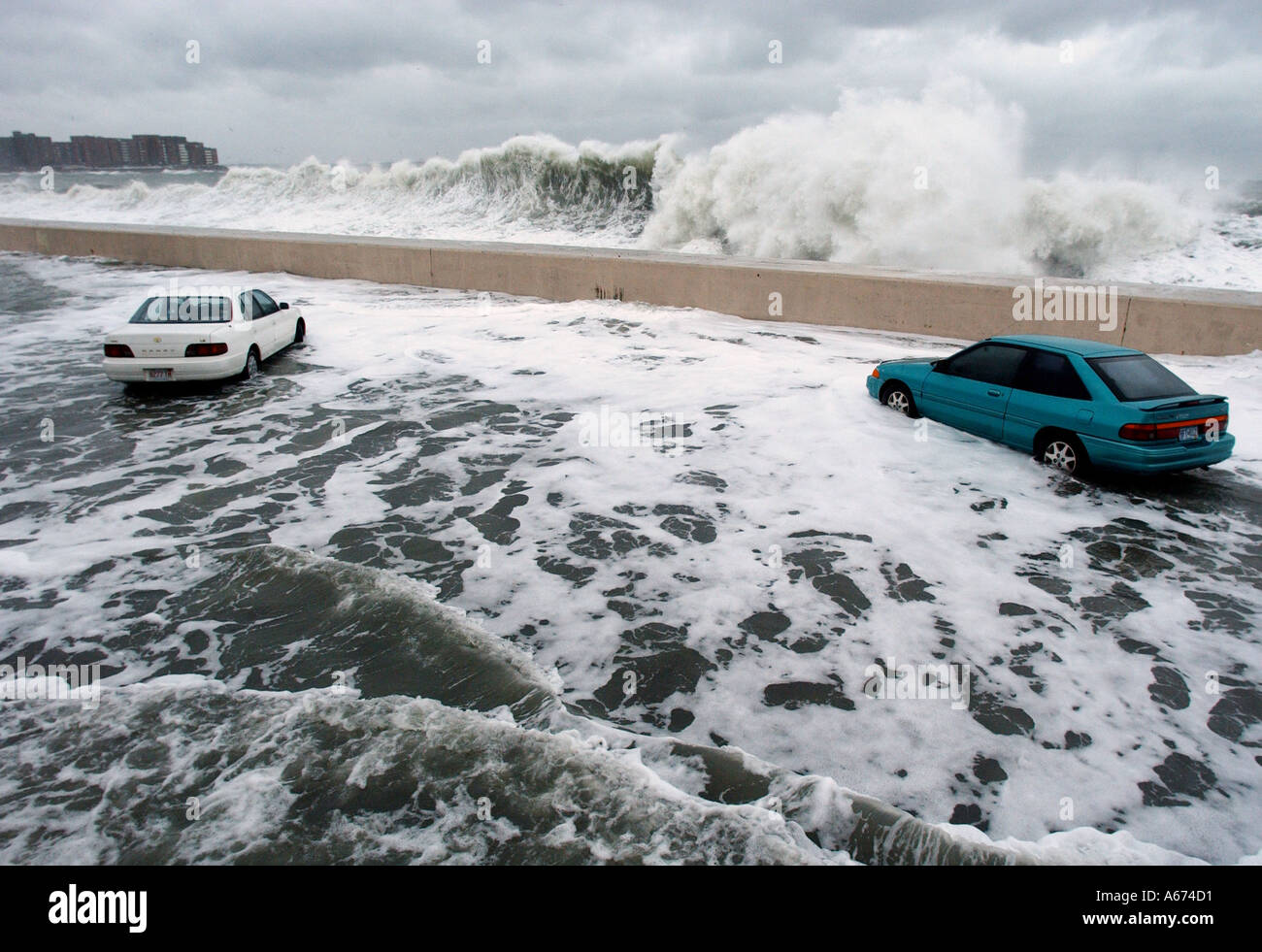Los vehículos están estancadas en las aguas de la inundación como olas gigantes crash en un rompeolas durante una tormenta de invierno en Massachusetts. Foto de stock