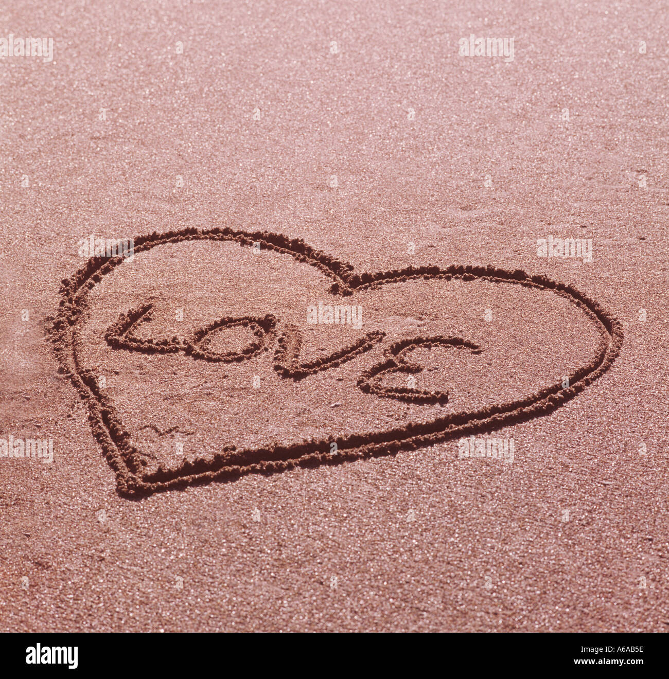 El amor de San Valentín símbolo dibujado en la arena en la playa Foto de stock