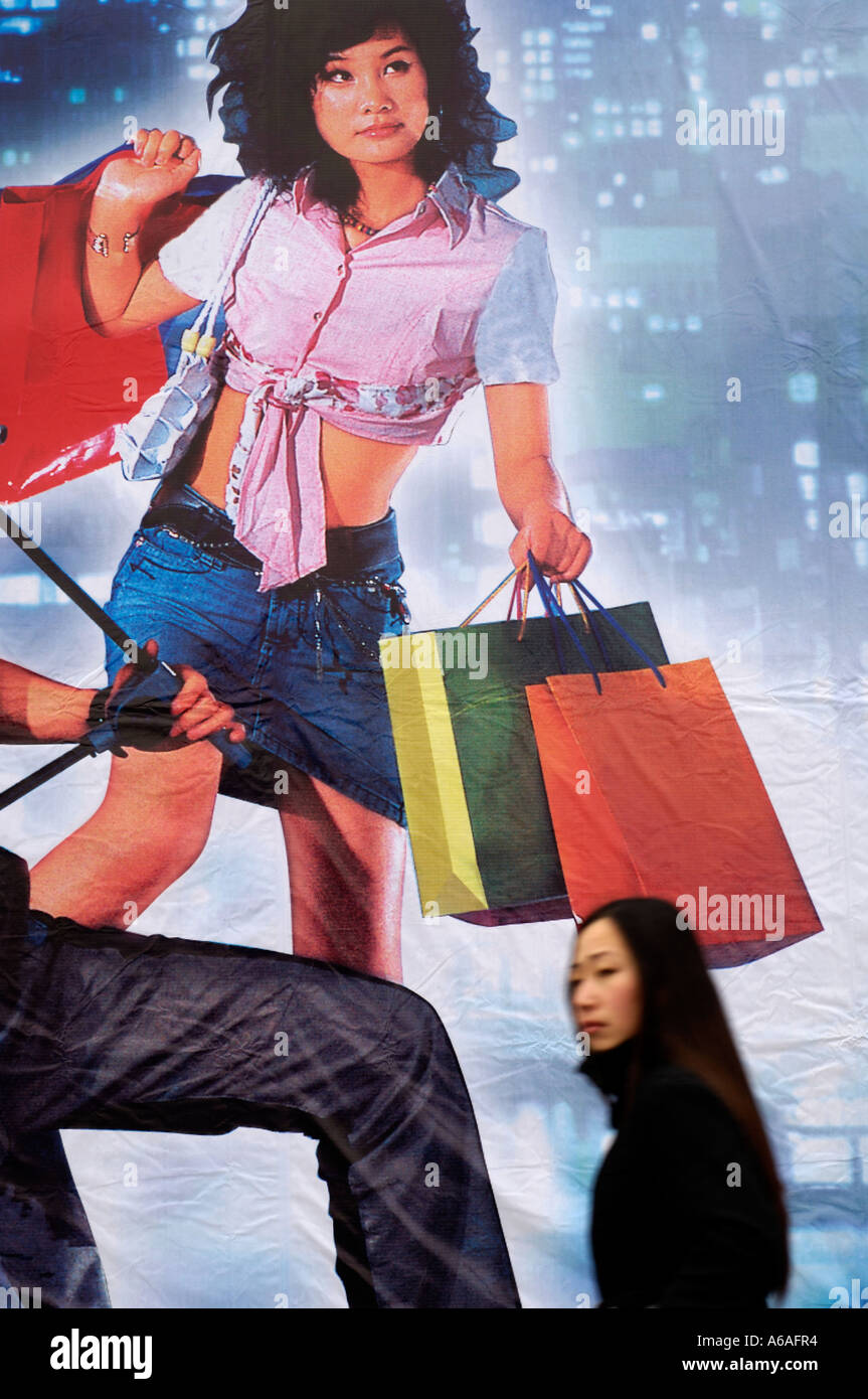 Una señora camina pasado una valla publicitaria con compras en la vida moderna de China en Beijing 2006-01-16 Foto de stock