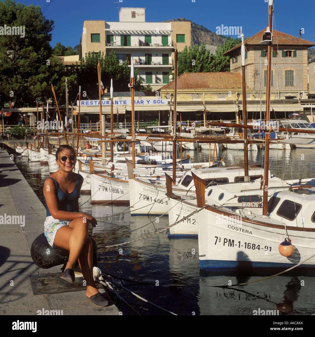 Chica con las tradicionales barcas de madera ( llauts ) en el Puerto de Soller, norte de Mallorca, Baleares, España. Foto de stock