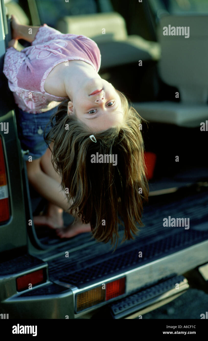 Chica colgando hacia atrás de la parte trasera del vehículo para mostrar su impaciencia Foto de stock