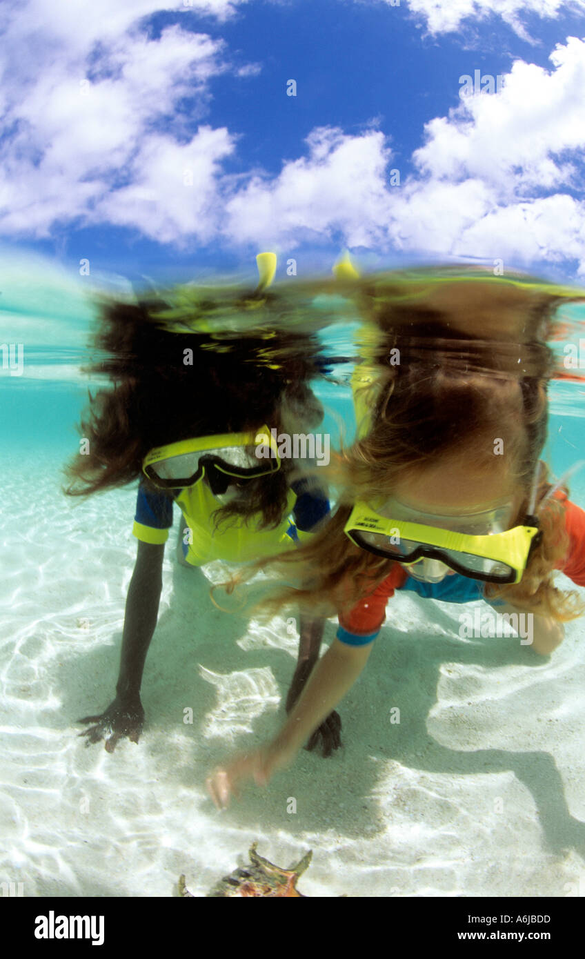 Dividir vista submarina de dos niñas snorkeling sobre arena blanca en el Pacífico Foto de stock