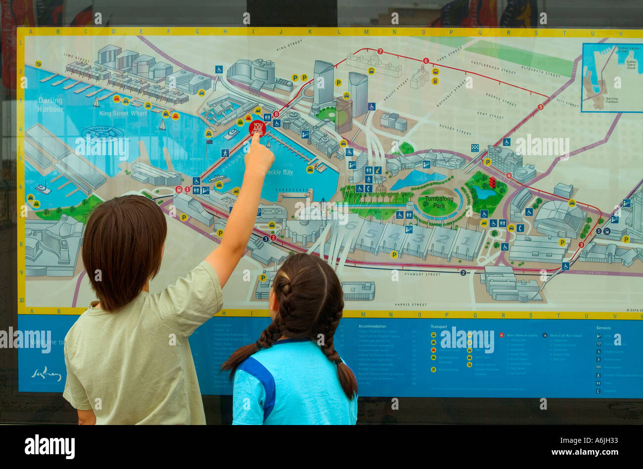 Dos niños usan un mapa de directorio de ciudades en Sydney, Australia para localizar su posición Foto de stock