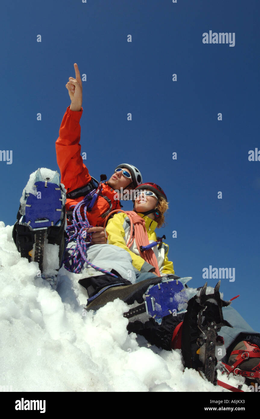 Montañero joven pareja sentada en la nieve Foto de stock