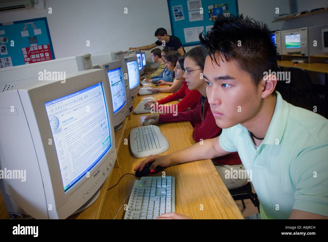 Adolescentes coreanas orientales 15-17 escuela equipo multicultural de clase superior de estudiantes adolescentes que estudian en sus puestos de trabajo en la escuela aula de informática Foto de stock