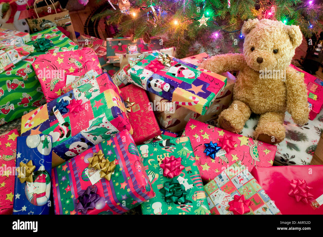Regalos envueltos y colocados bajo el árbol de navidad para ser abiertos  por jóvenes alegres en navidad mañana un oso de peluche también se sitúa  donde fue entregado por santa claus Fotografía