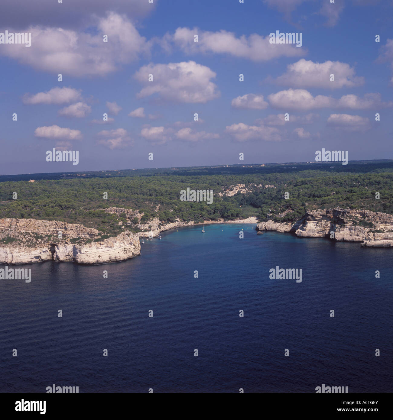 Vista aérea - remoto costa con acantilados, bosques interiores y cala de arena / bay / anchorage - Sur Oeste de Menorca / Menorca, B Foto de stock