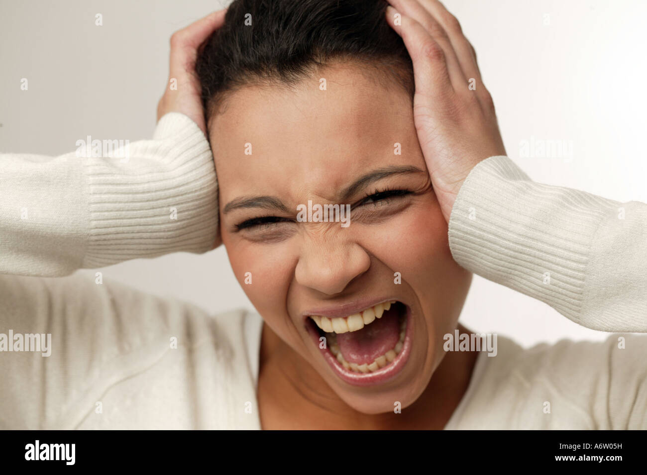 Gritando joven sosteniendo su cabeza con sus manos Foto de stock