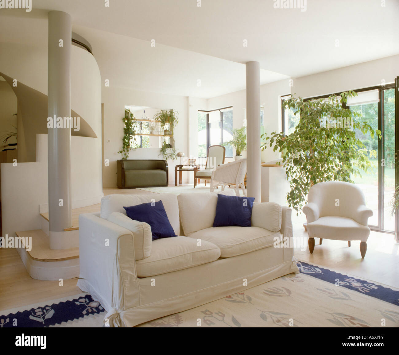 Sofá blanco con cojines azules en openplan salon blanco y moderno  Fotografía de stock - Alamy