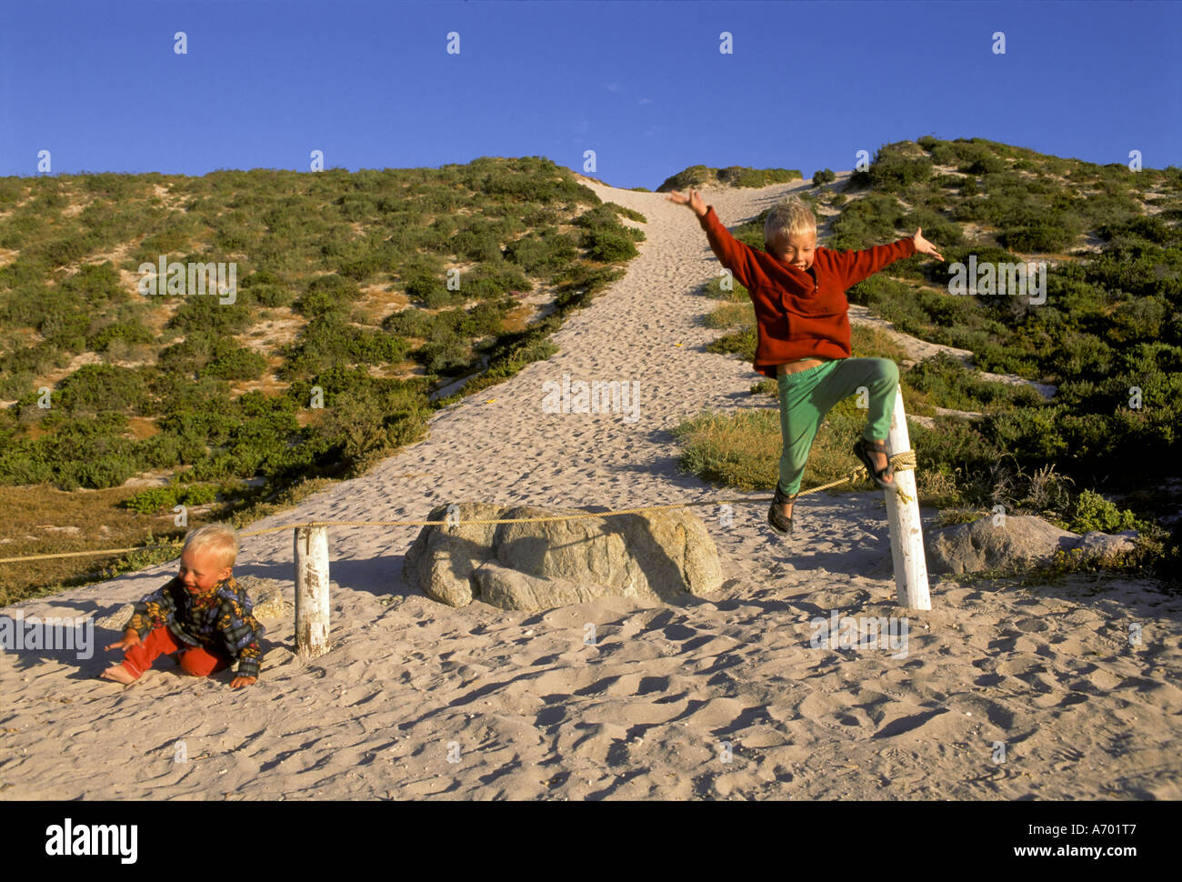 Los niños pequeños están saltando a través de un cable en una duna, Tittis Bay, Sudáfrica Foto de stock