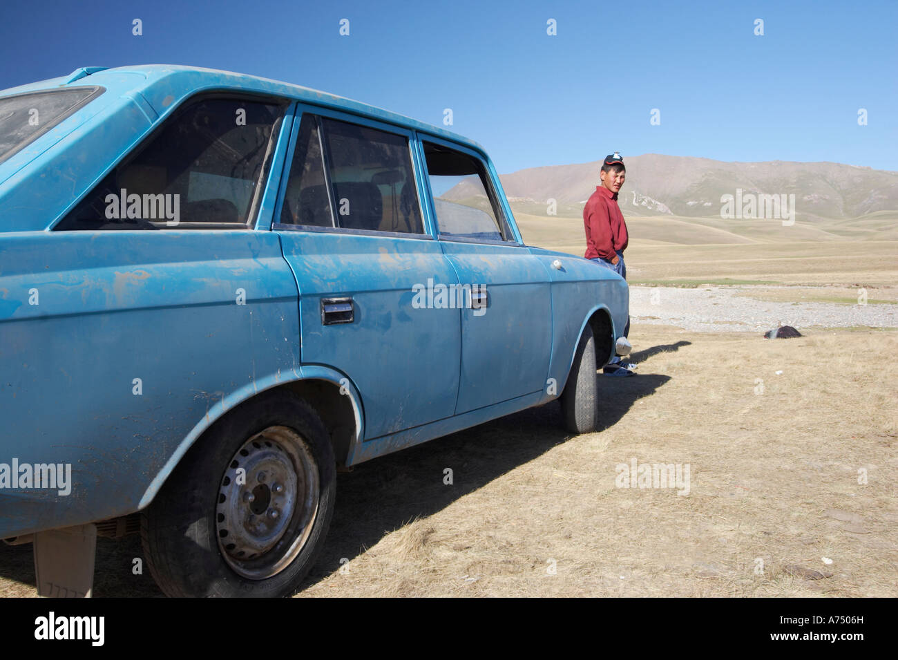 Hombre Kirguise de pie junto al viejo coche comunista Foto de stock