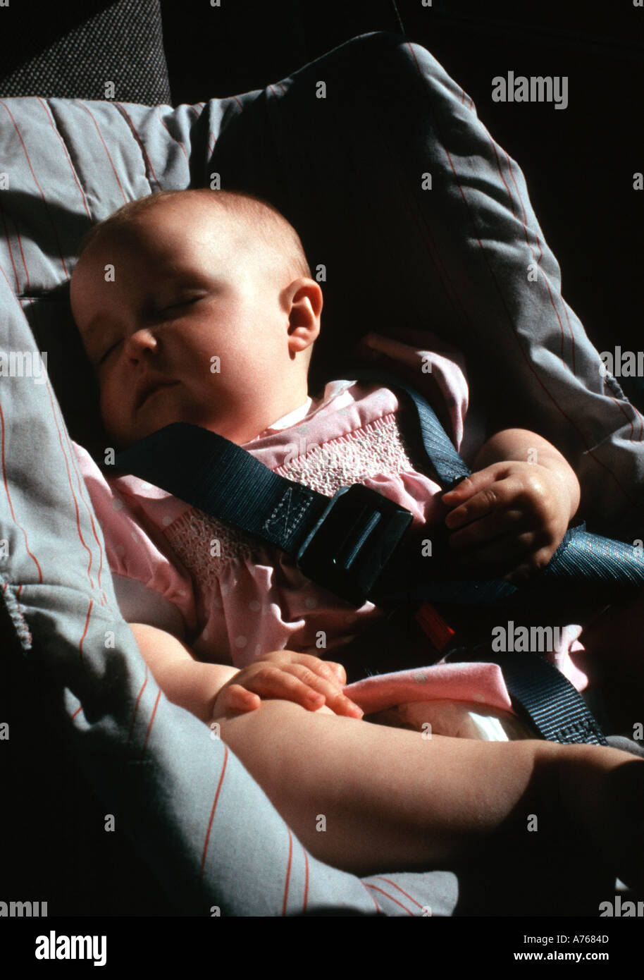 Bebé dormido en un asiento para niños en la parte trasera de un coche, hija del fotógrafo Foto de stock