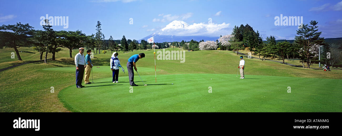 Los hombres japoneses con caddy femenino jugando al golf bajo el Monte Fuji en la isla de Honshu Foto de stock