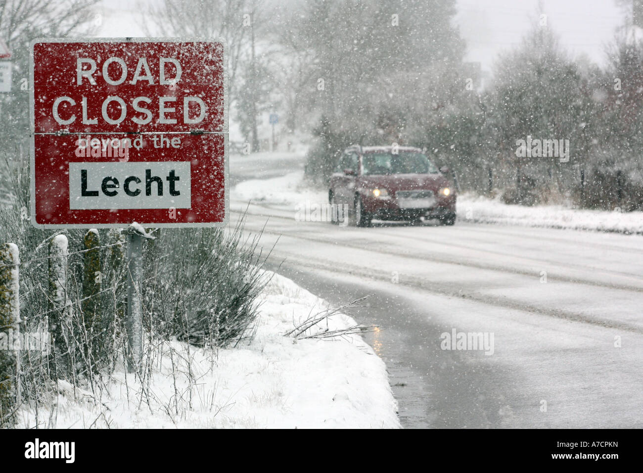Coche de conducción a través de Blizzard durante tiempo de nieve en el invierno pasado el cartel de cerrado por carretera cerca del centro de esquí lecht Aberdeenshire Foto de stock