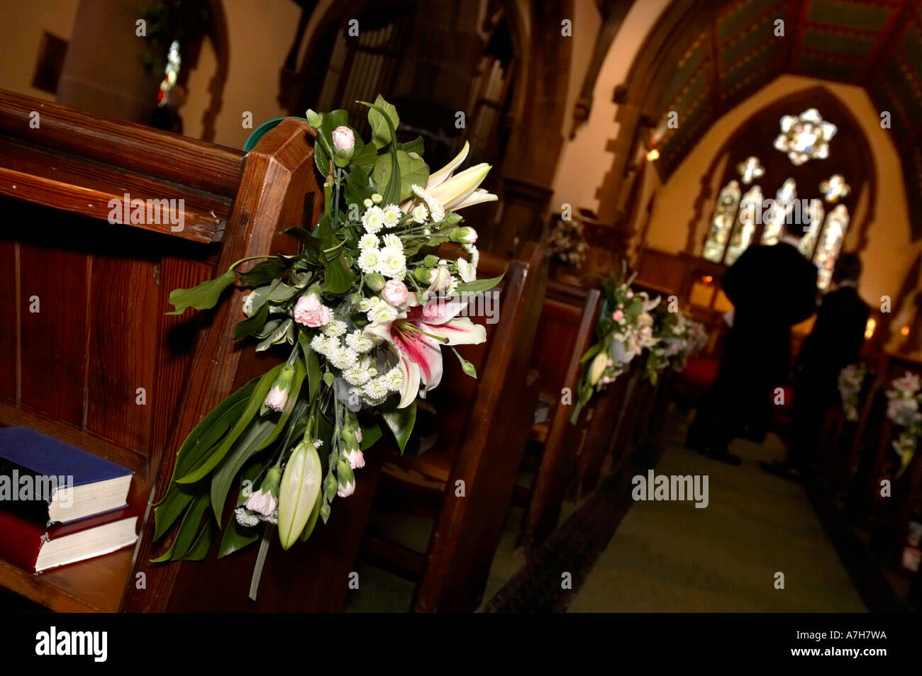 Ver el pasillo en una iglesia, mostrando las flores en el extremo de una banca justo antes de una boda Foto de stock