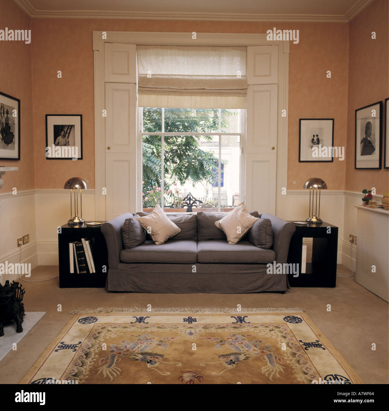 Gray sofá delante de la ventana con persianas blancas y ciego de melocotón  adosado salón con fotografías en blanco+negro enmarcadas Fotografía de  stock - Alamy