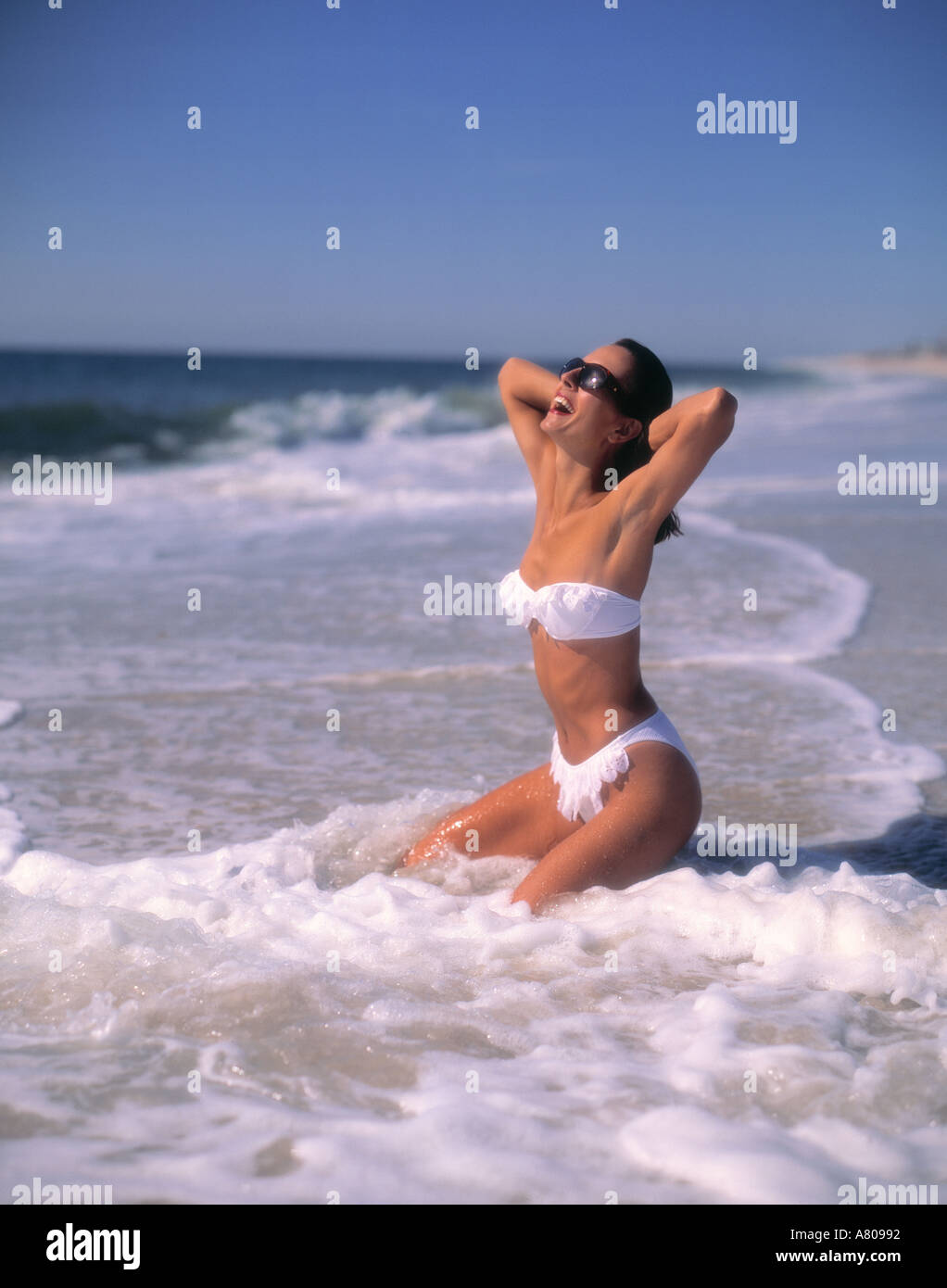 Mujer en traje de baño sentada en Surf on Beach Atlantic Ocean Southampton New York Estados Unidos 25, 30, 35 años Foto de stock