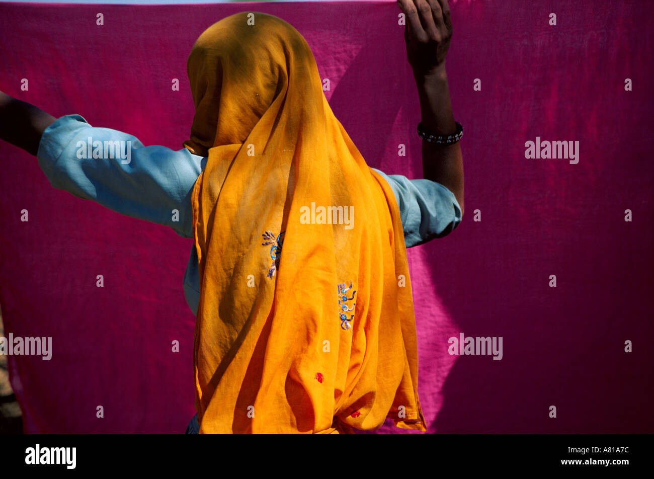 Mujer en naranja colgando un sari en Rajastán, India Foto de stock
