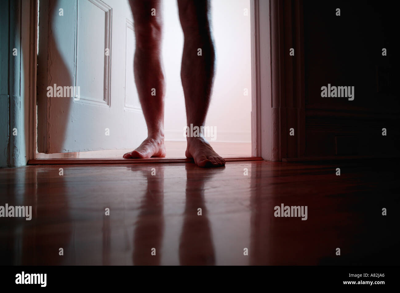 Hombre desnudo de pie en la puerta abierta (ángulo de visión baja, baja sección) Foto de stock