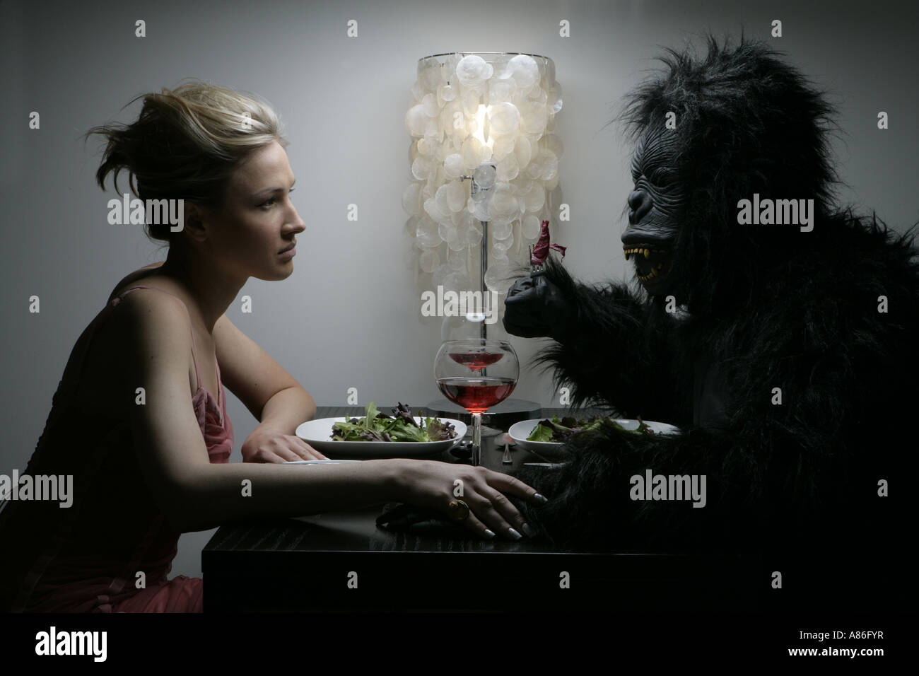 Una mujer es cenar con un hombre en un traje de gorila. Foto de stock