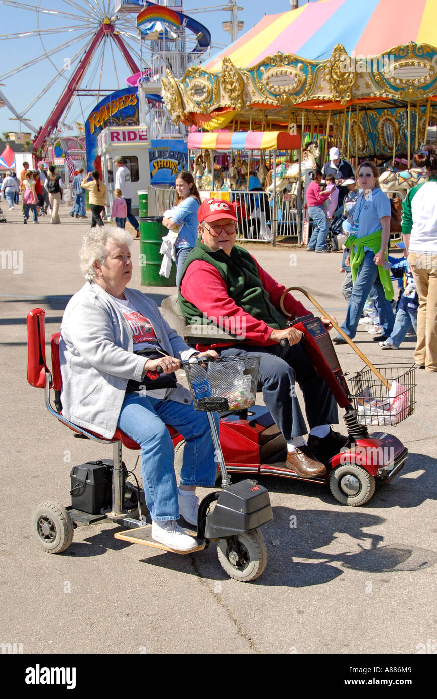 Senior hombre y mujeres usan sillas de rueda para conseguir alrededor de la Feria Estatal de Florida, en Tampa Foto de stock